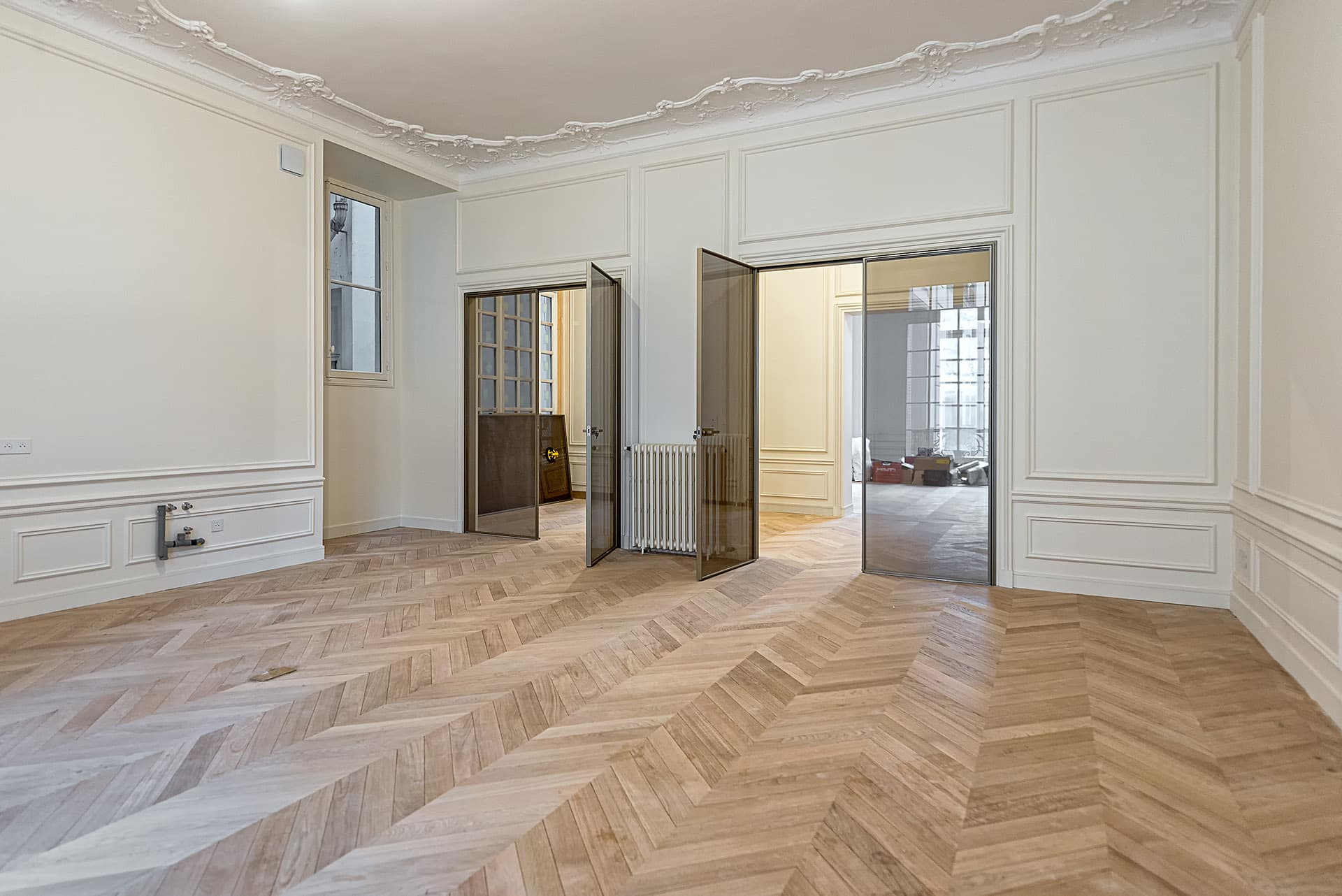 Pièce de réception avec verrières en acier et parquet à chevrons